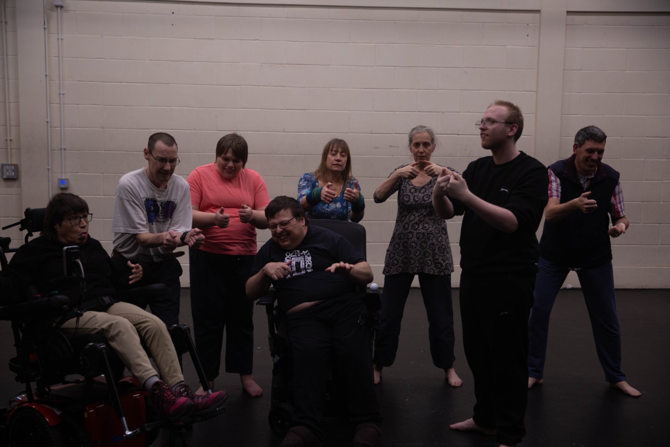 Rehearsing 'Computer Games' in new work in preparation by Eddie Wadsworth called In My Younger Years: Jen-Jo Bartholemew-Biggs, David Bartholemew Biggs, Arlene James, Eddie Wadsworth, Agnieszka Michalik, Karen Rush, Sam Cleeton, Sam Evans. Eight persons in casual clothes: five are standing, and two are sitting in wheelchairs. They all act as if they were playing a console game.